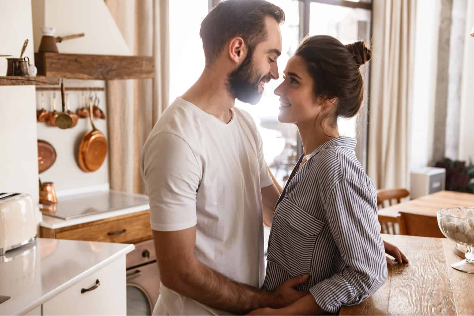 un homme et une femme se tiennent enlacés dans la cuisine