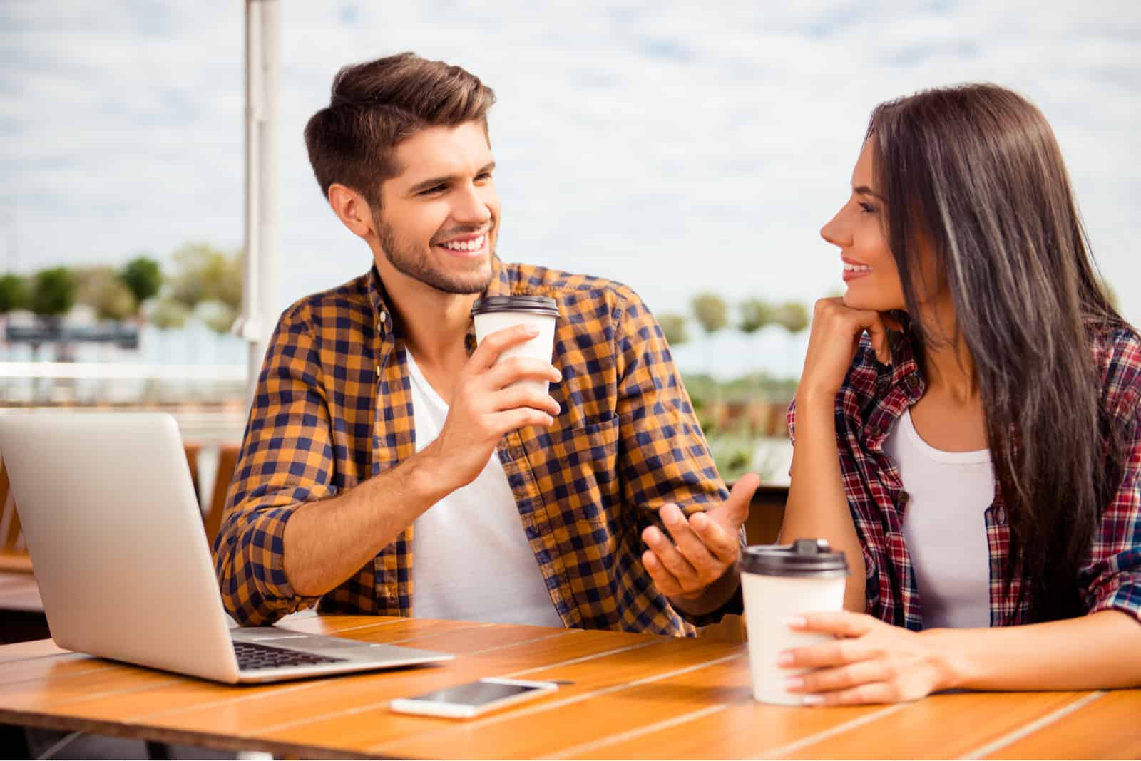un homme et une femme souriants assis à l'extérieur en train de parler