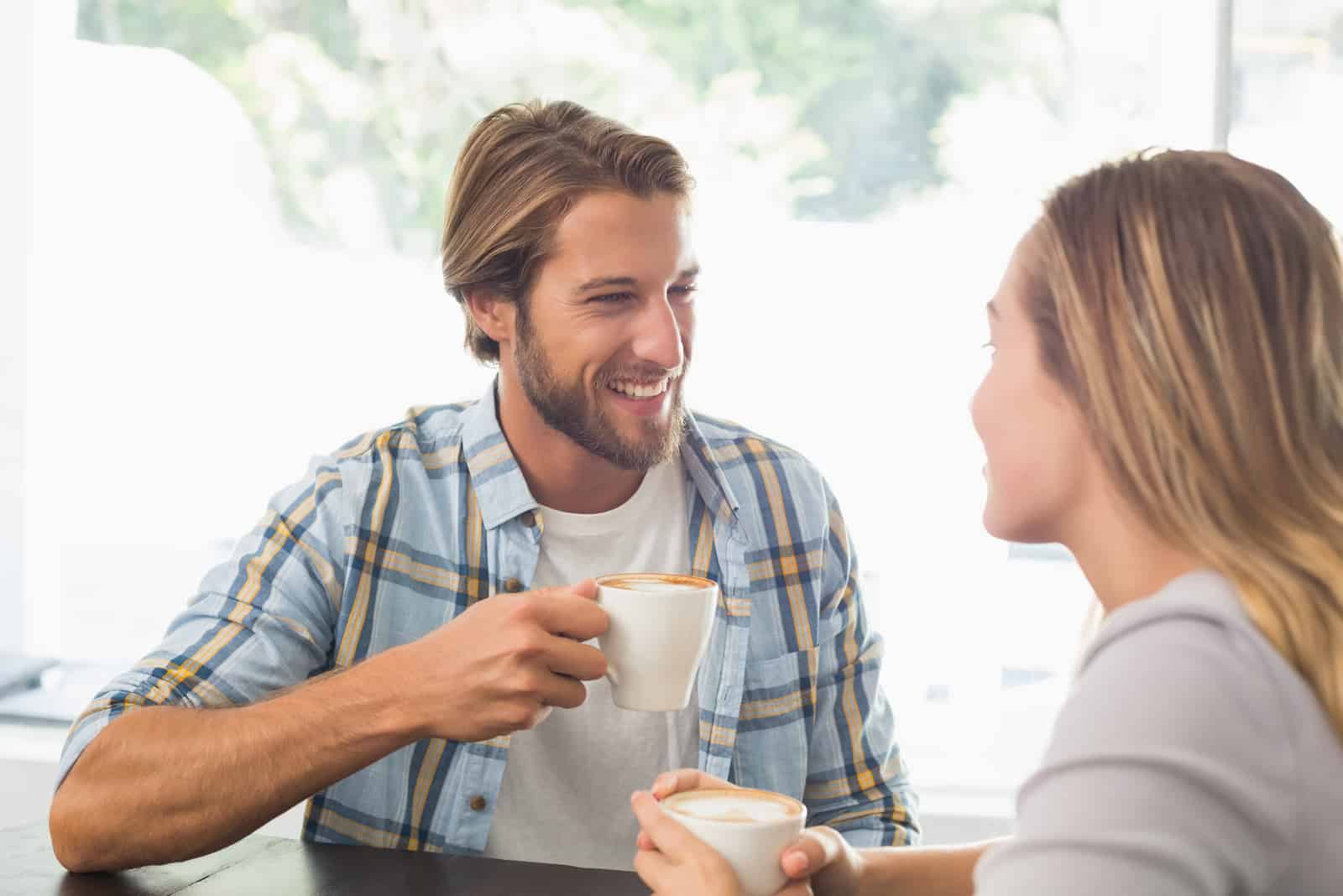 un homme et une femme souriants buvant du café et parlant