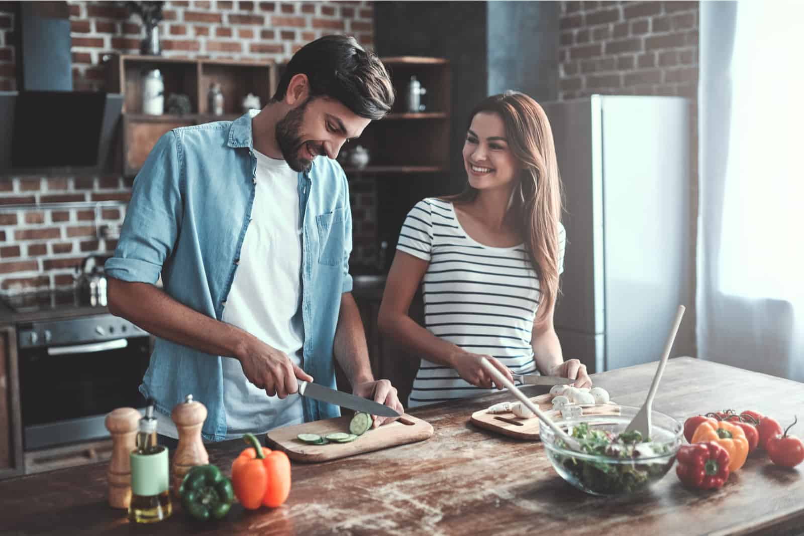 un homme et une femme souriants cuisinant ensemble dans la cuisine
