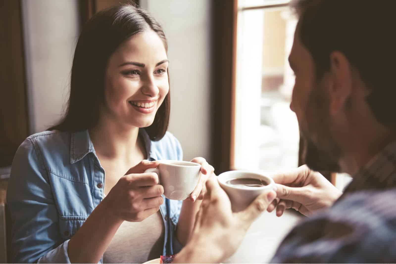 un homme et une femme souriants s'assoient et boivent du café