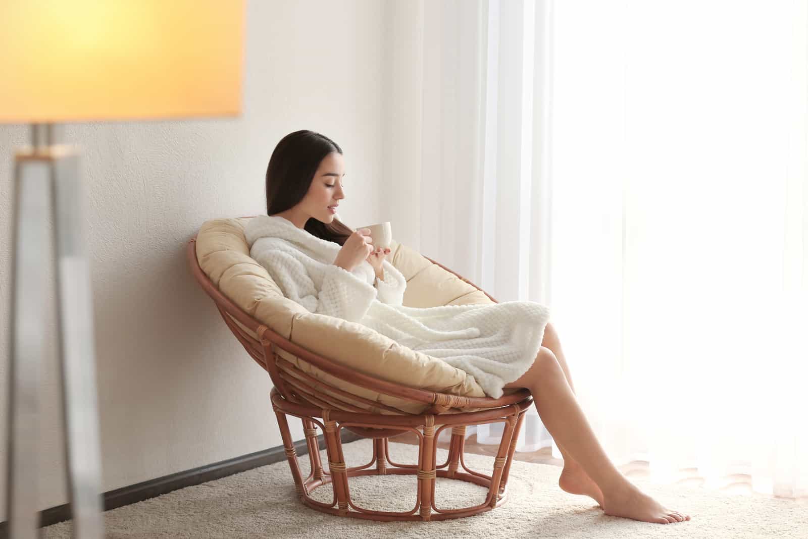 une femme en peignoir assise sur une chaise buvant du café