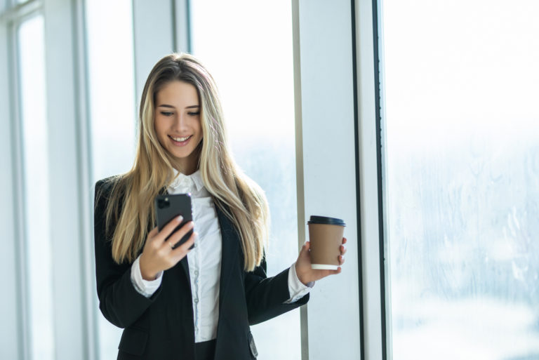 femme tenant un téléphone et un café