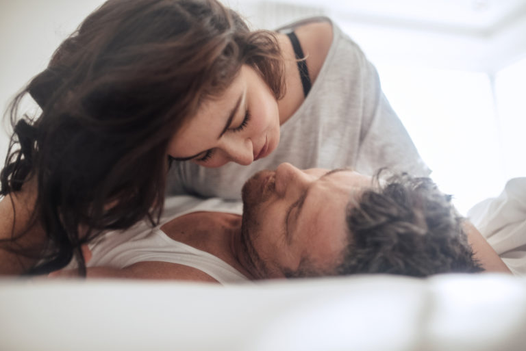 une belle femme aux longs cheveux noirs au lit câlinant un homme