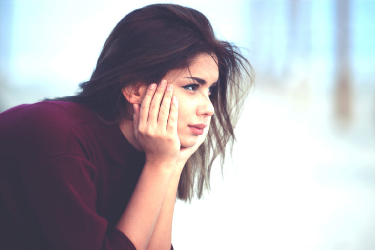 une belle femme aux longs cheveux noirs est assise pensivement et regarde au loin