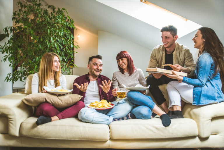 un groupe d'amis souriants s'assoient sur le canapé et parlent