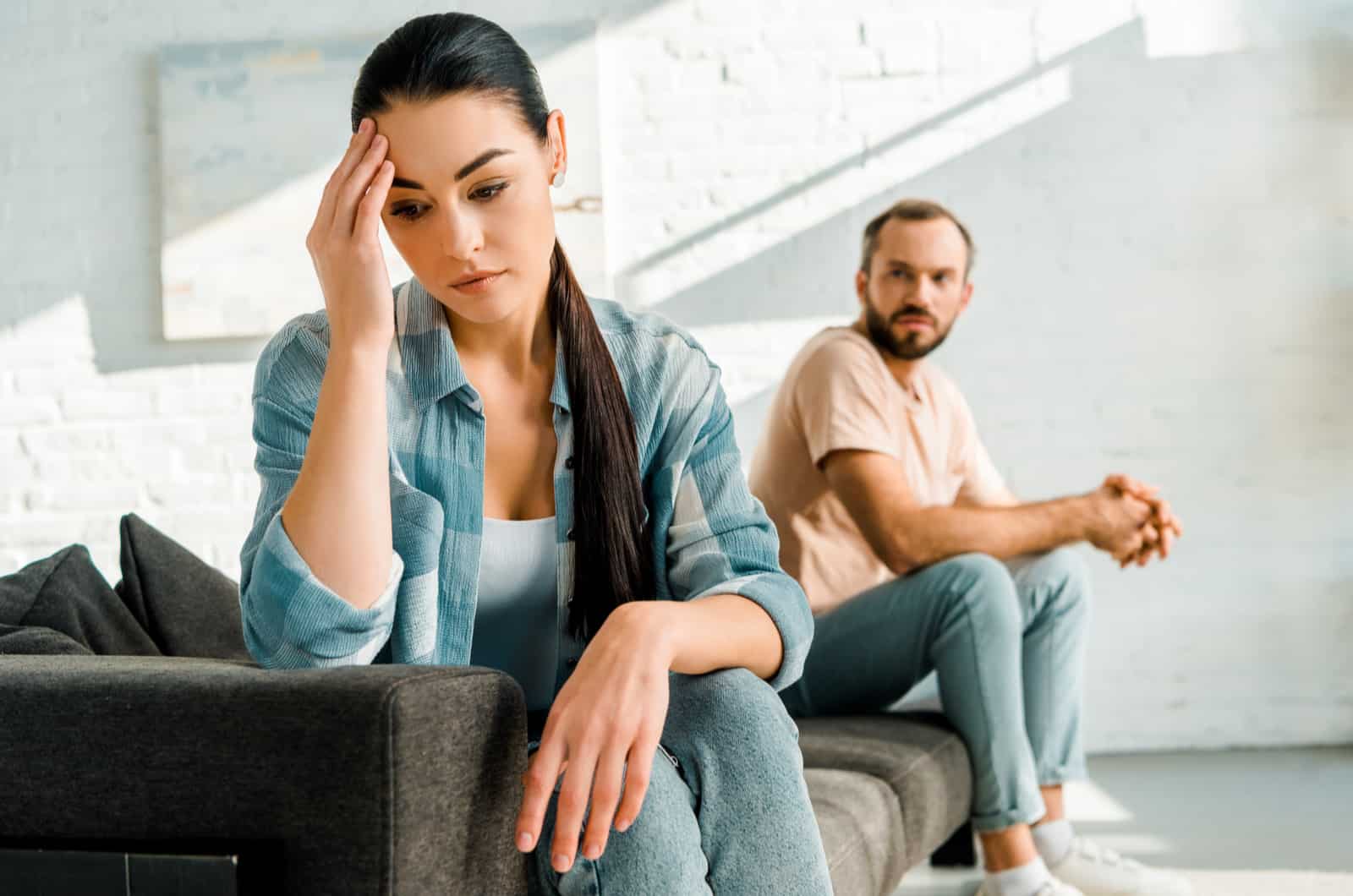 femme tenant sa tête avec un homme en arrière-plan