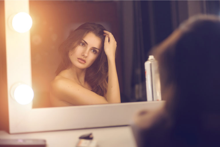 une femme aux longs cheveux bruns se regarde dans le miroir