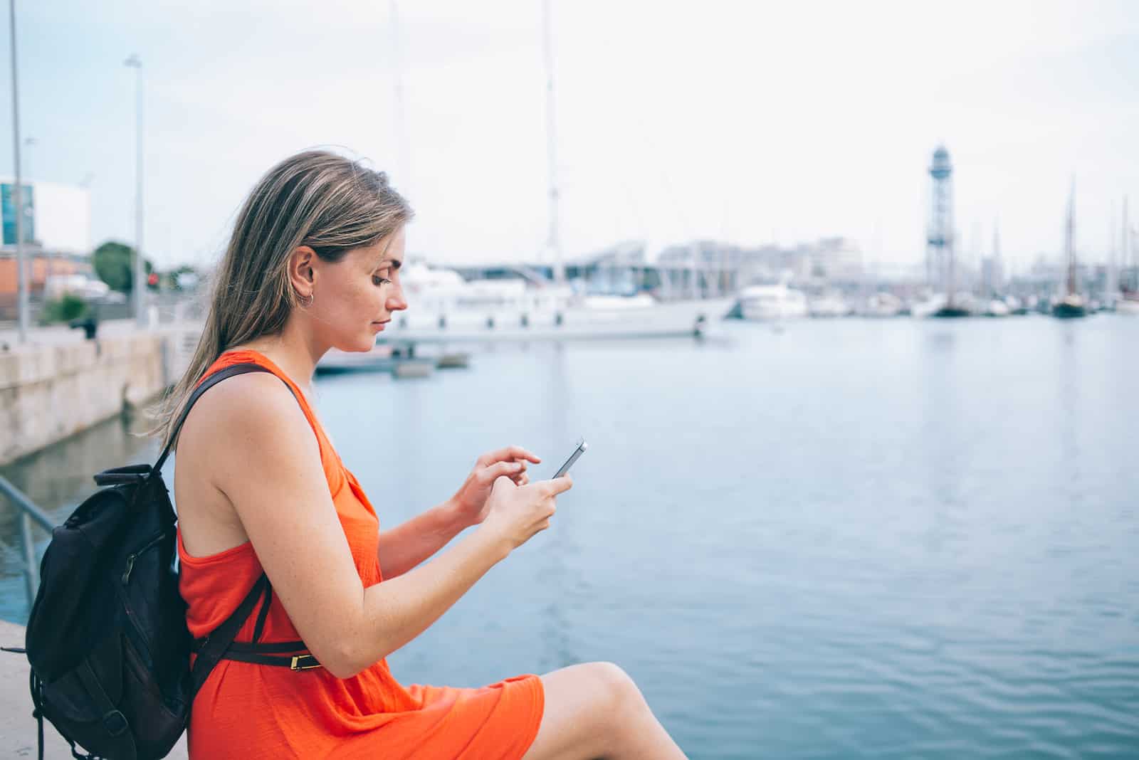 belle femme assise au bord de la mer et bouton sur téléphone portable