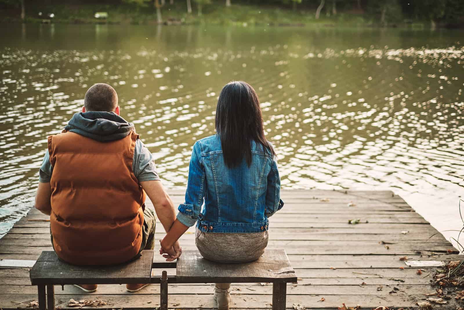 couple assis au bord du lac main dans la main