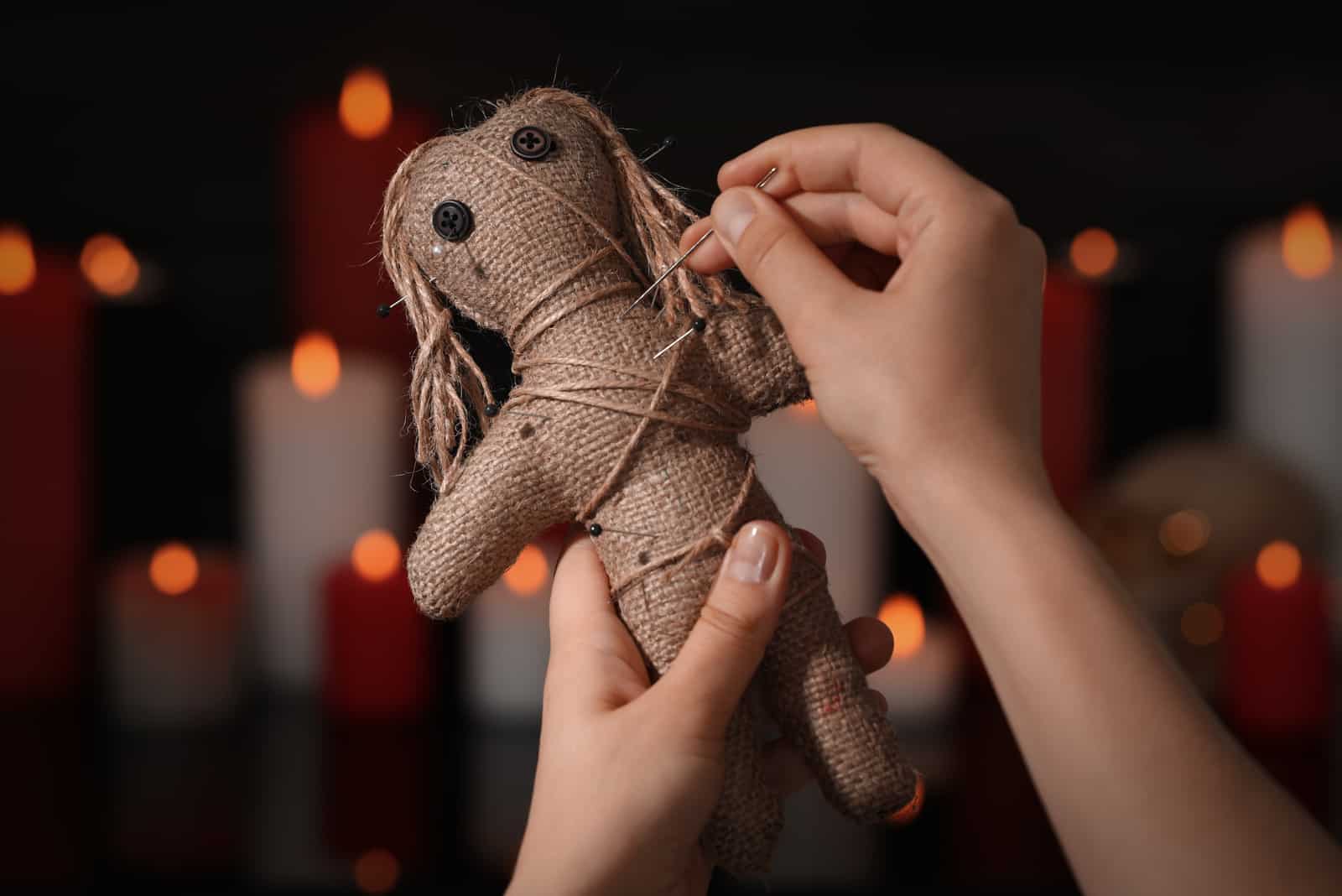 femme mettant une aiguille dans une poupée vaudou