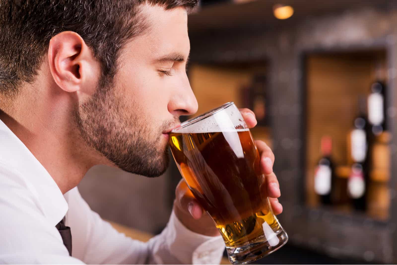 jeune homme buvant une bière au verre