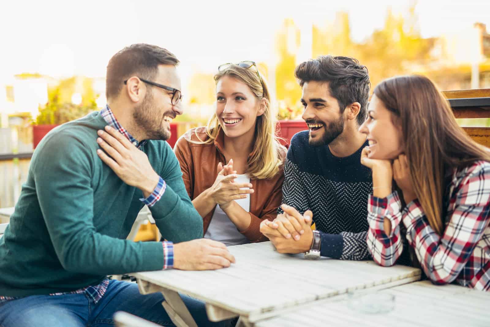 un groupe d'amis à l'extérieur à une table en train de parler