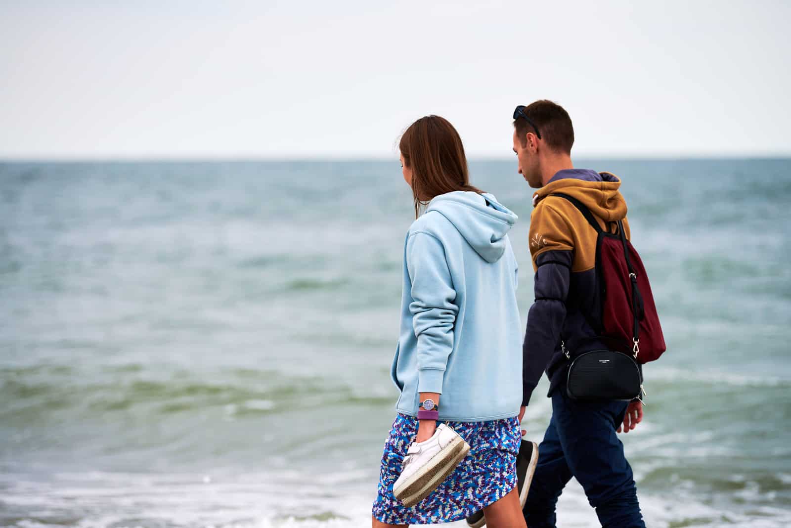 un homme et une femme se tenant la main et marchant le long de la plage