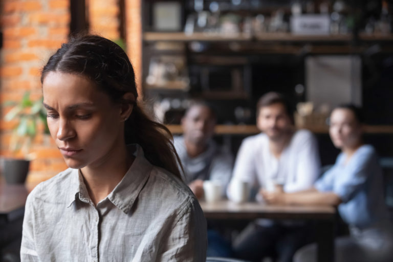 un groupe de personnes parlant derrière le dos d'une femme sur le lieu de travail