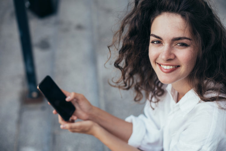 jeune femme aux cheveux bouclés tenant un téléphone