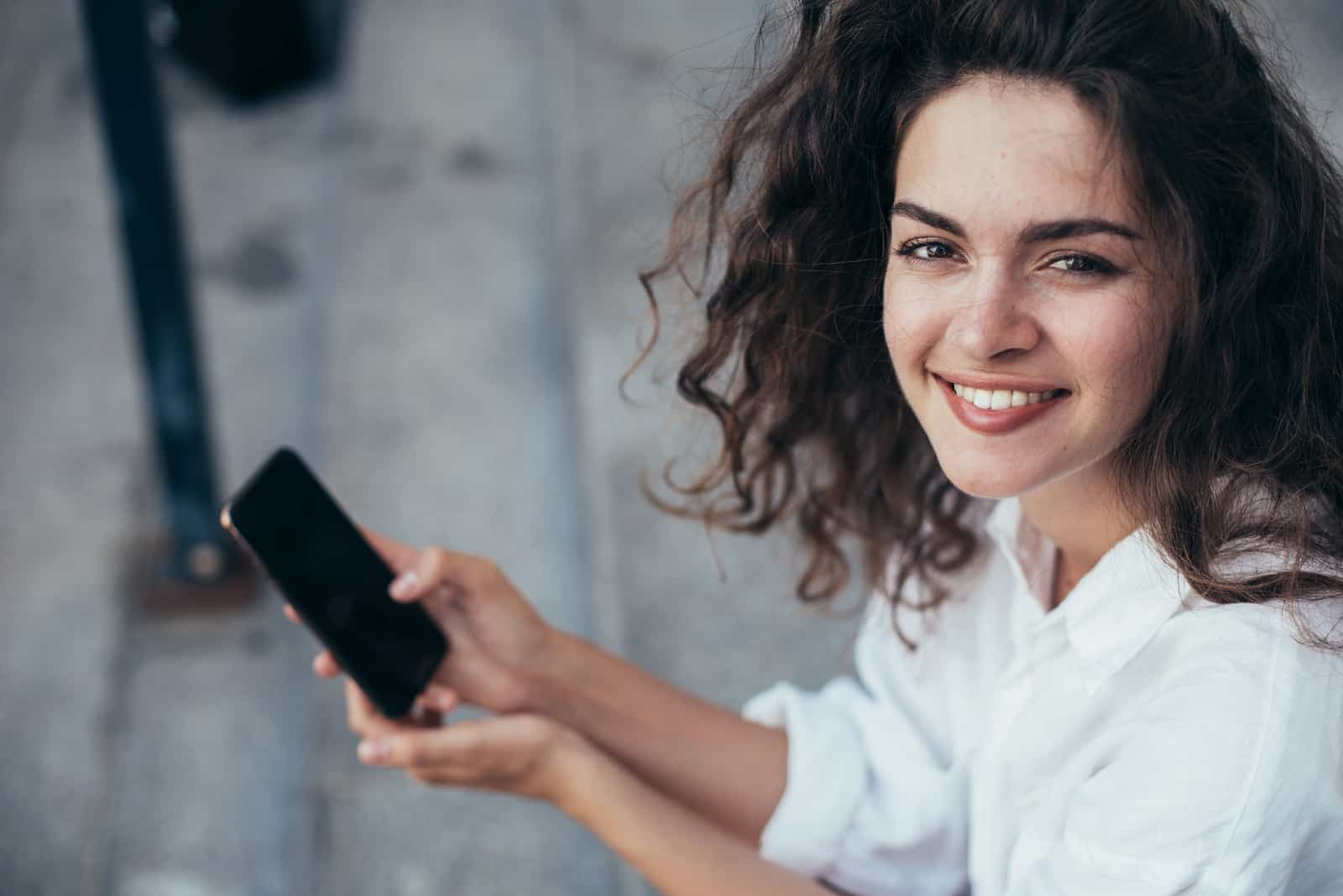 jeune femme aux cheveux bouclés tenant un téléphone