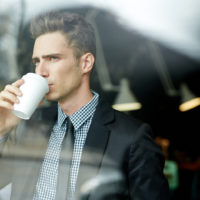 homme buvant du café regardant par la fenêtre