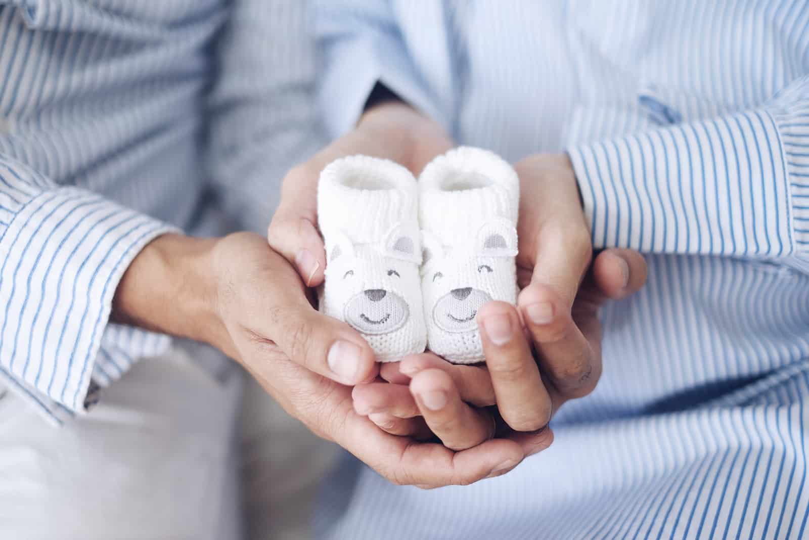 futurs parents tenant de jolies chaussures de bébé