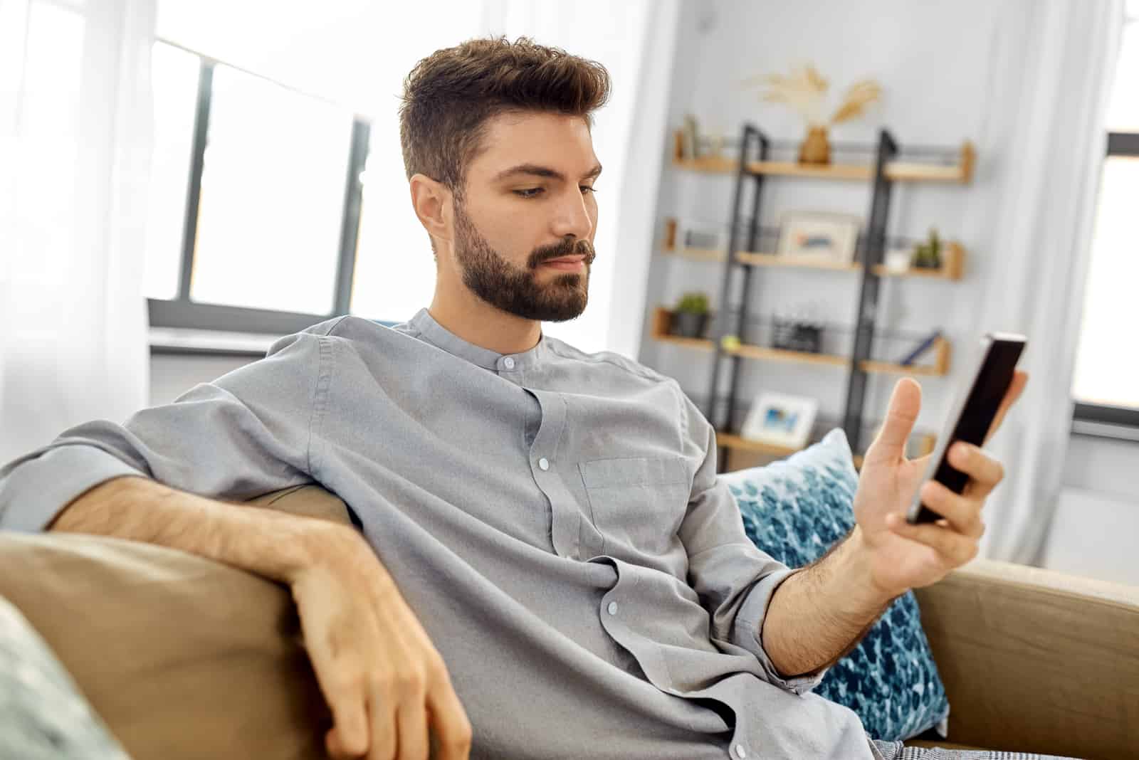 jeune homme assis sur un canapé envoyant des SMS