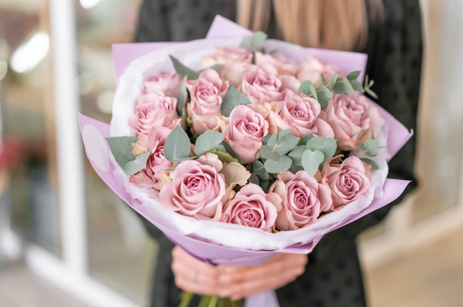 Beau bouquet de roses violettes pastel dans les mains de la femme