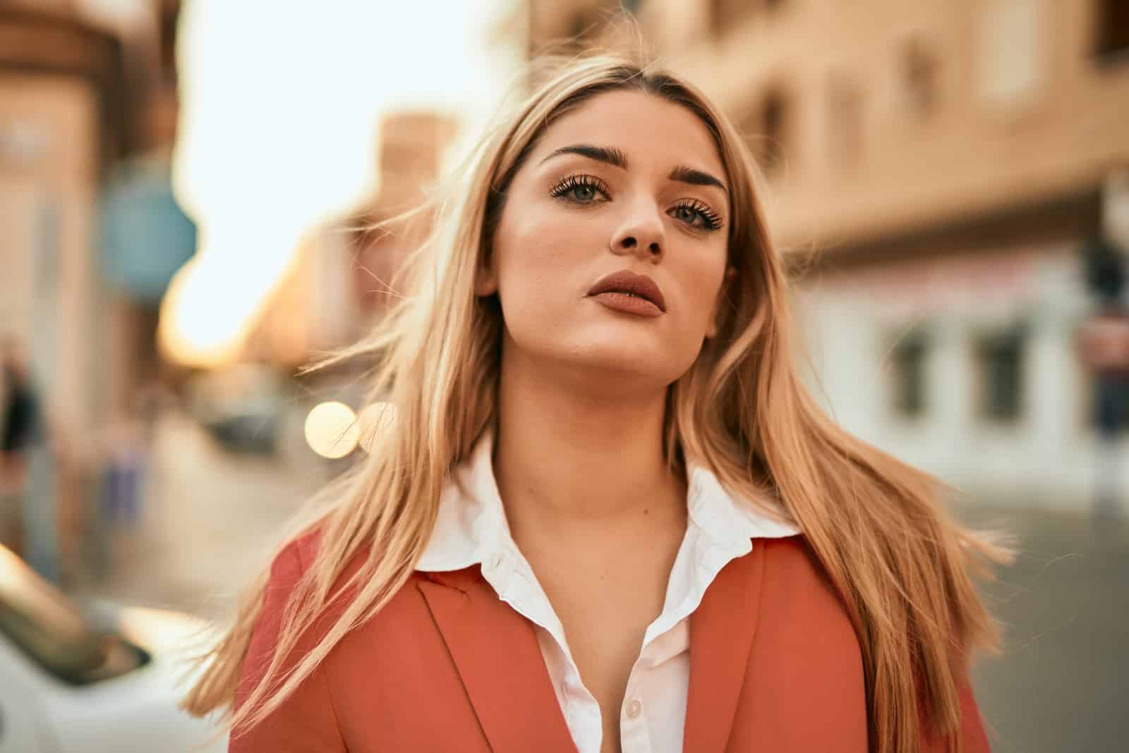 Jeune femme d'affaires blonde avec une expression sérieuse debout dans la ville