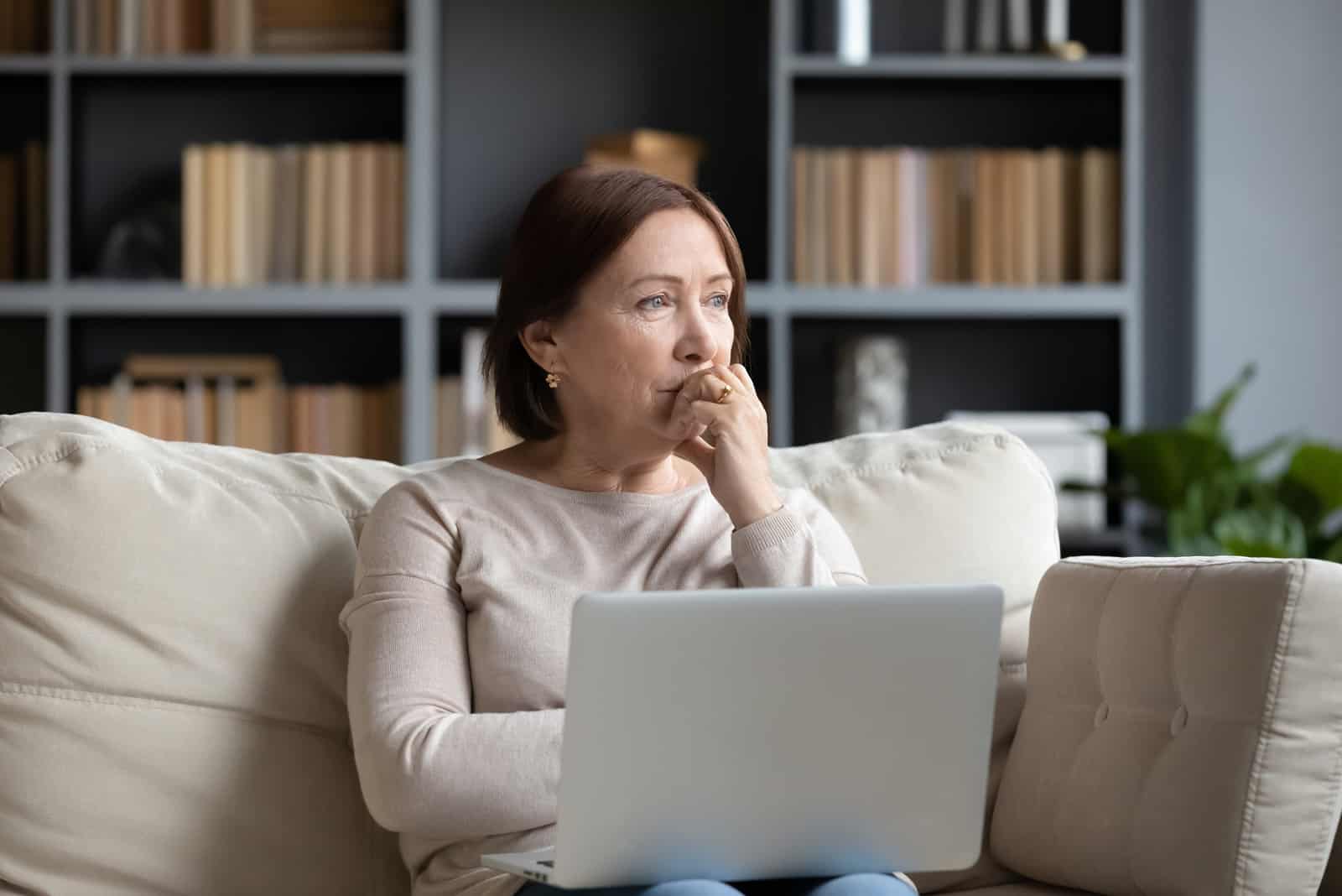 triste femme d'âge moyen assise sur un canapé