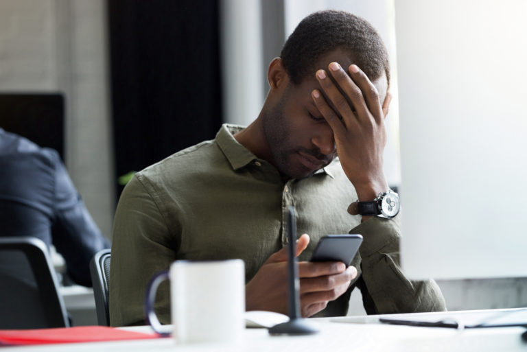 homme bouleversé assis dans un café lisant ses messages