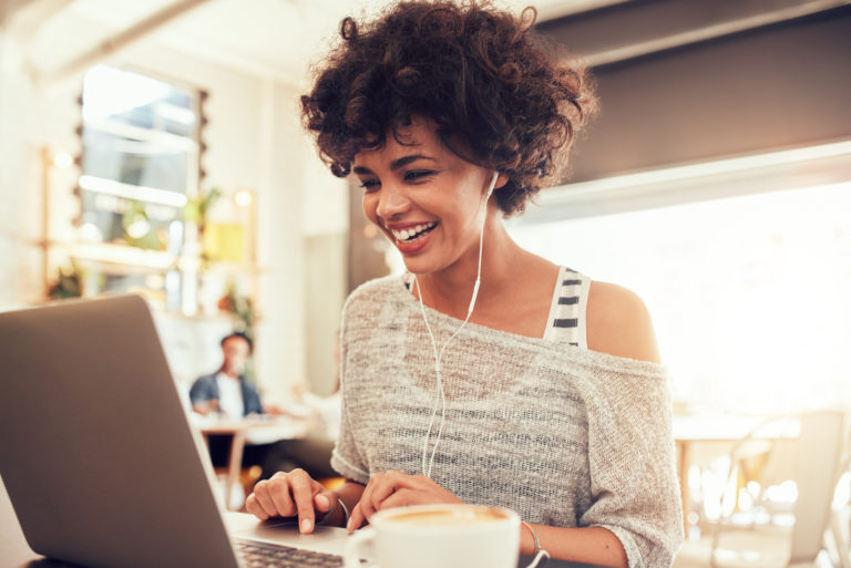 une femme souriante est assise devant son ordinateur portable et parle