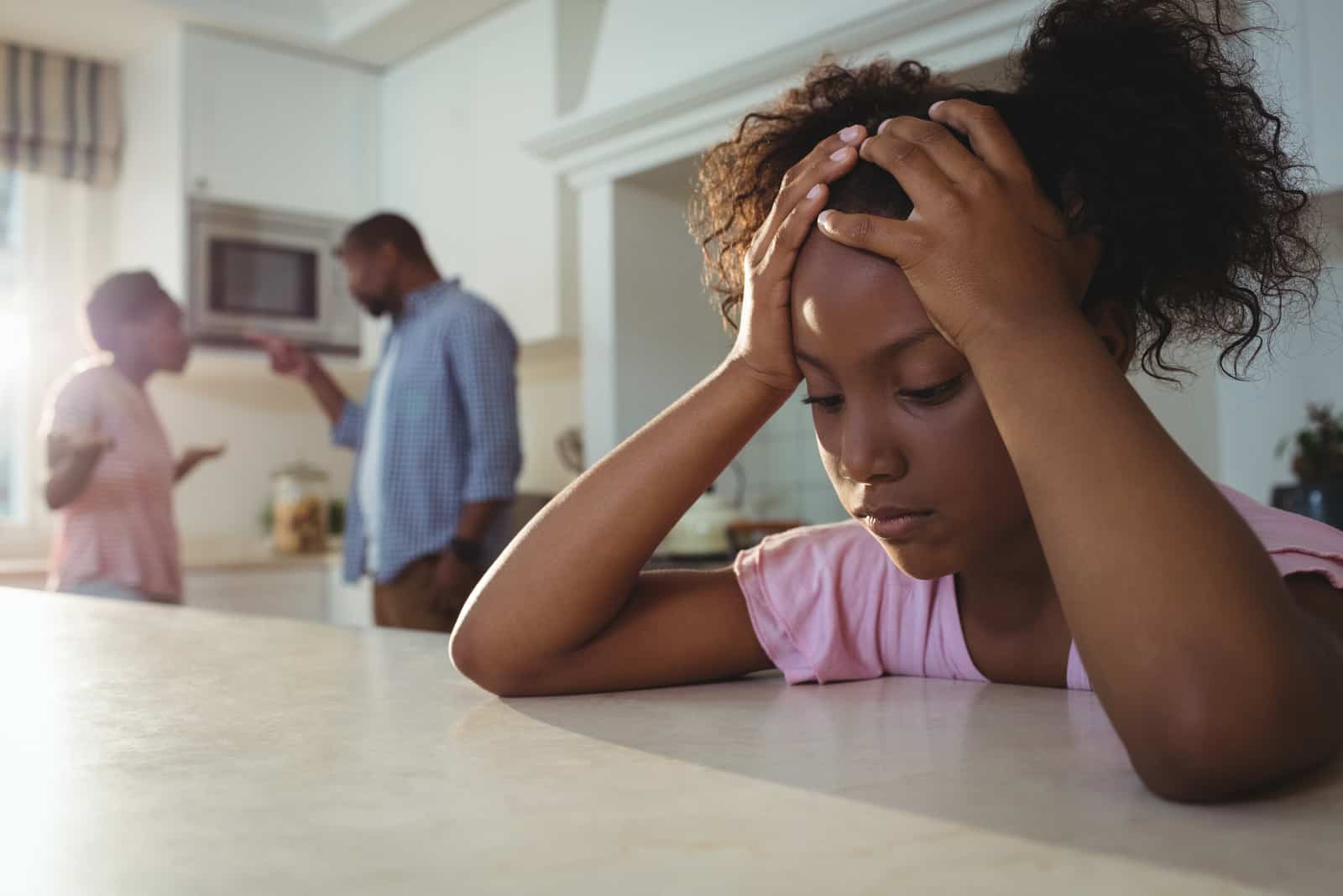 Une fille triste écoute ses parents se disputer dans la cuisine à la maison