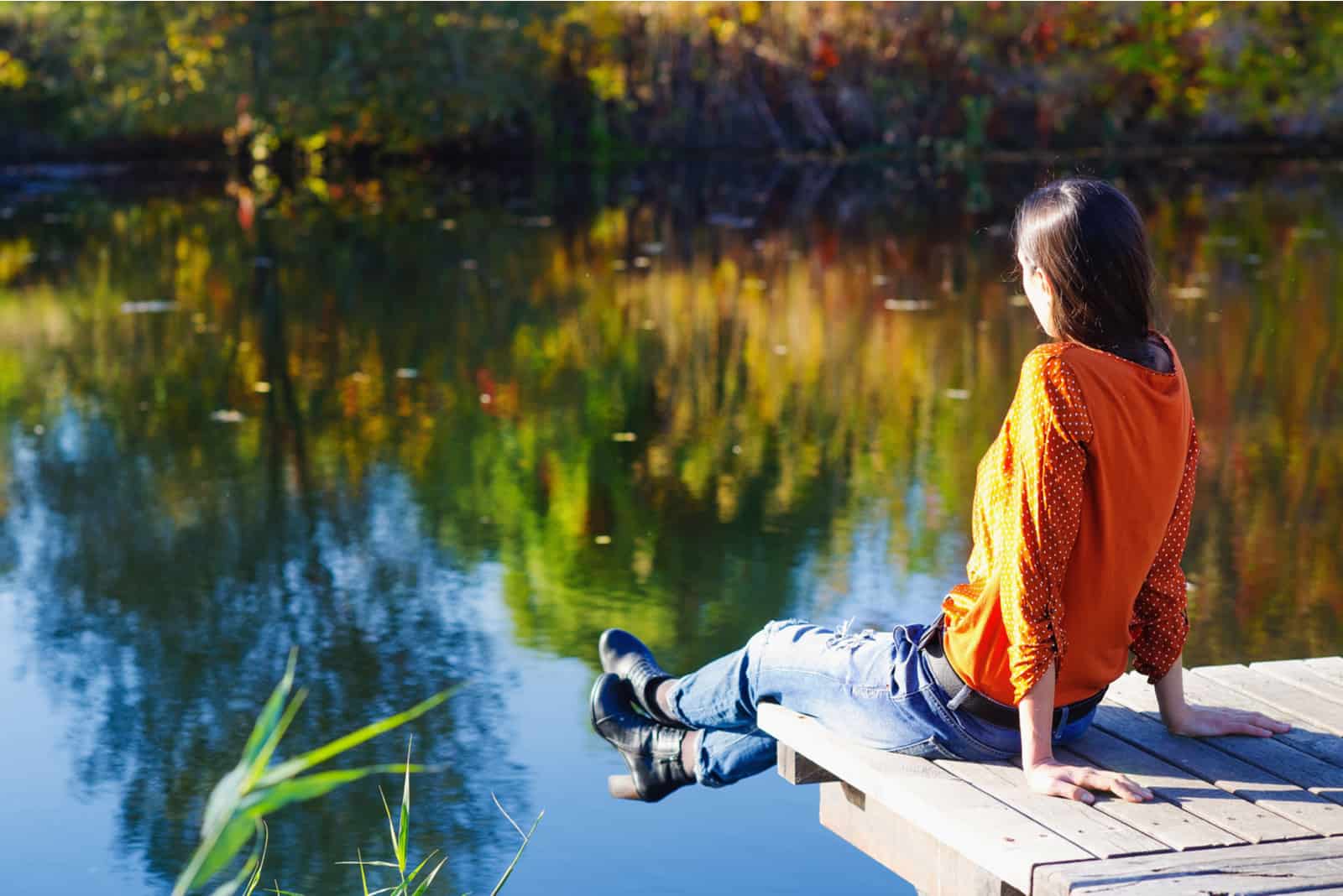femme assise sur le pont regardant le lac