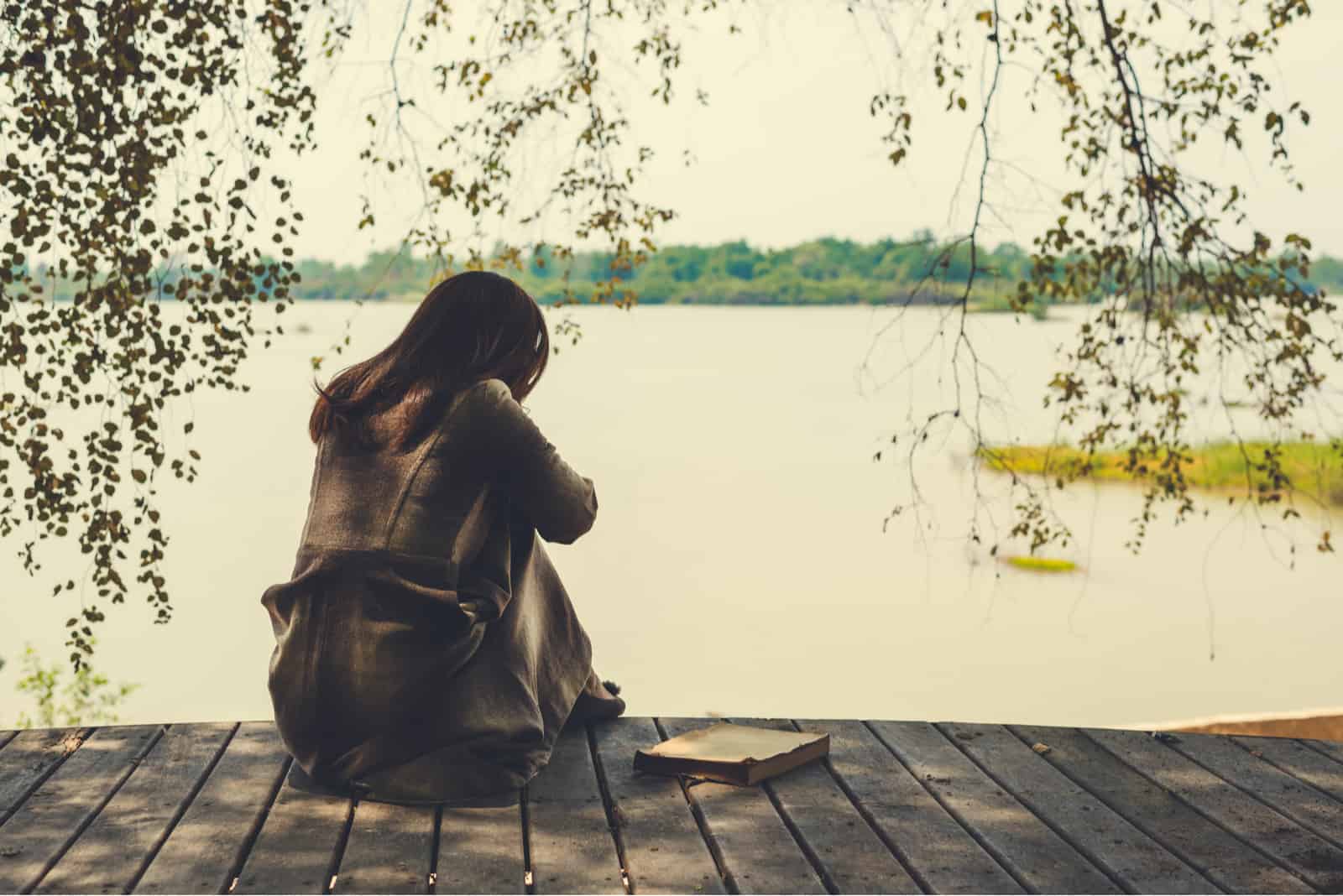 femme assise sur un quai au bord d'un lac