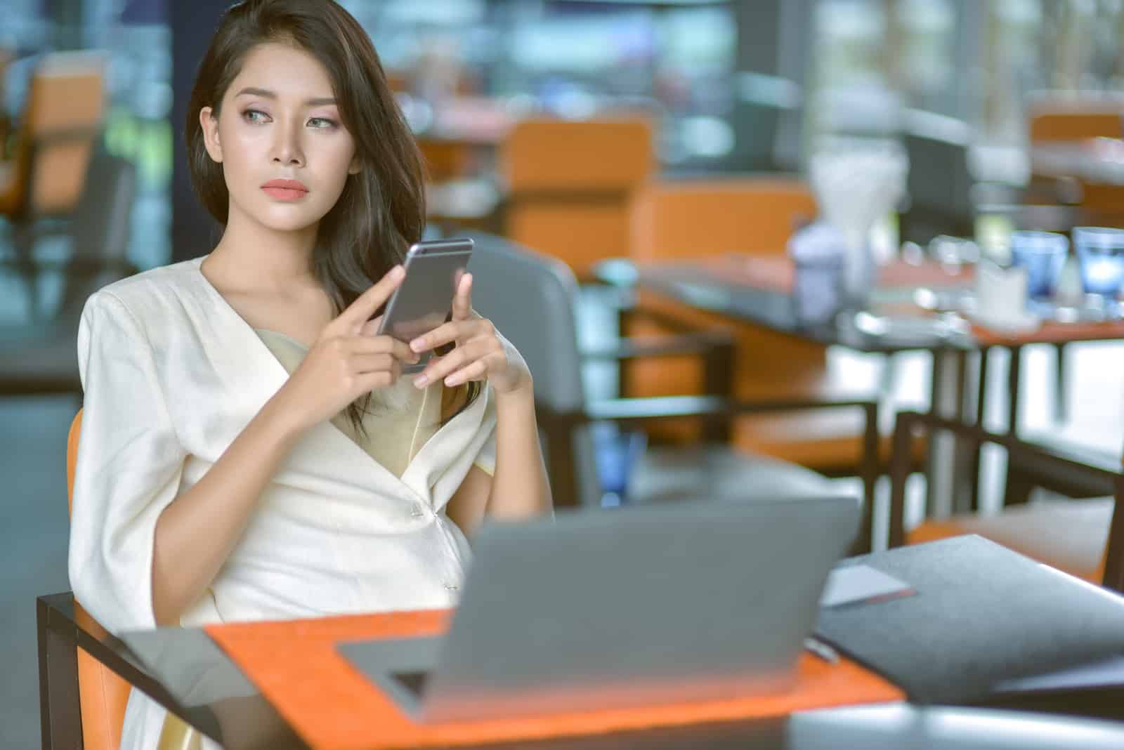 femme d'affaires sérieuse assise près de la table avec le téléphone à la main