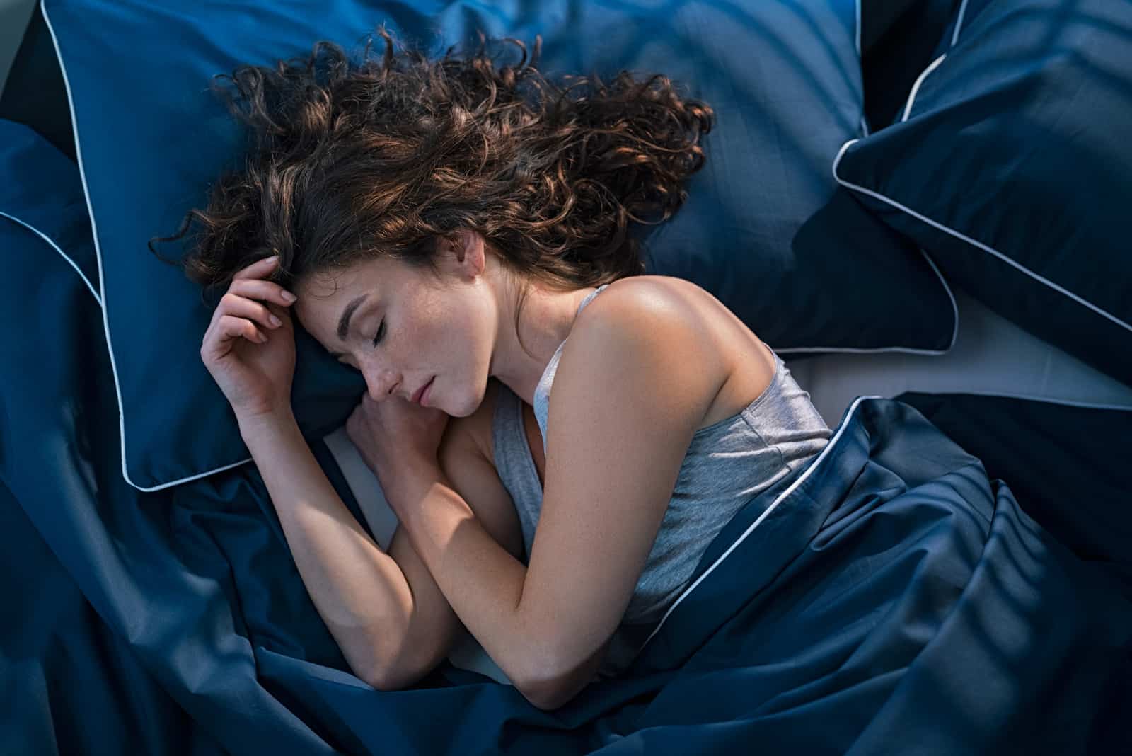 femme dormant dans son lit avec des draps bleus