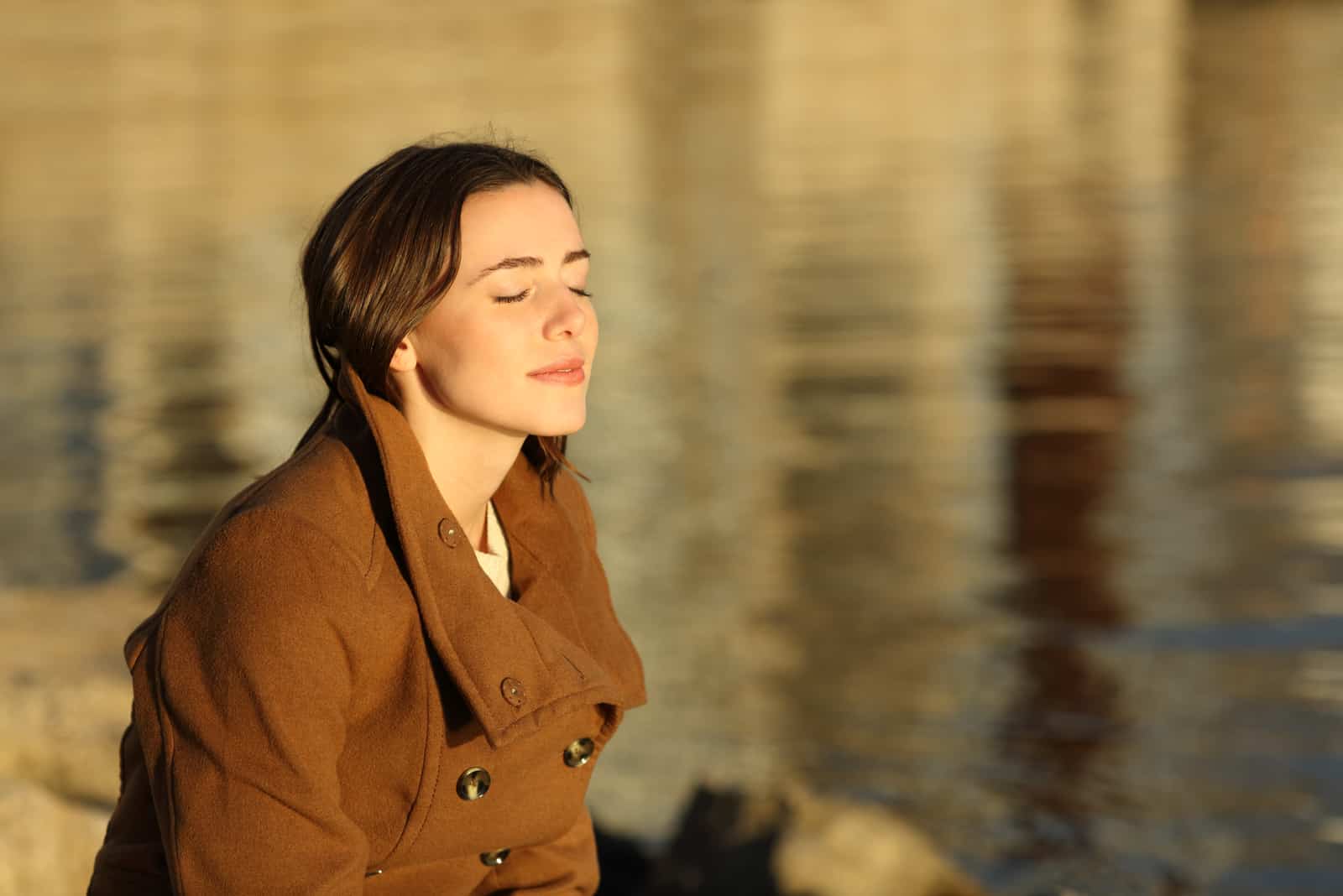 fille assise au bord de la rivière en profitant du soleil