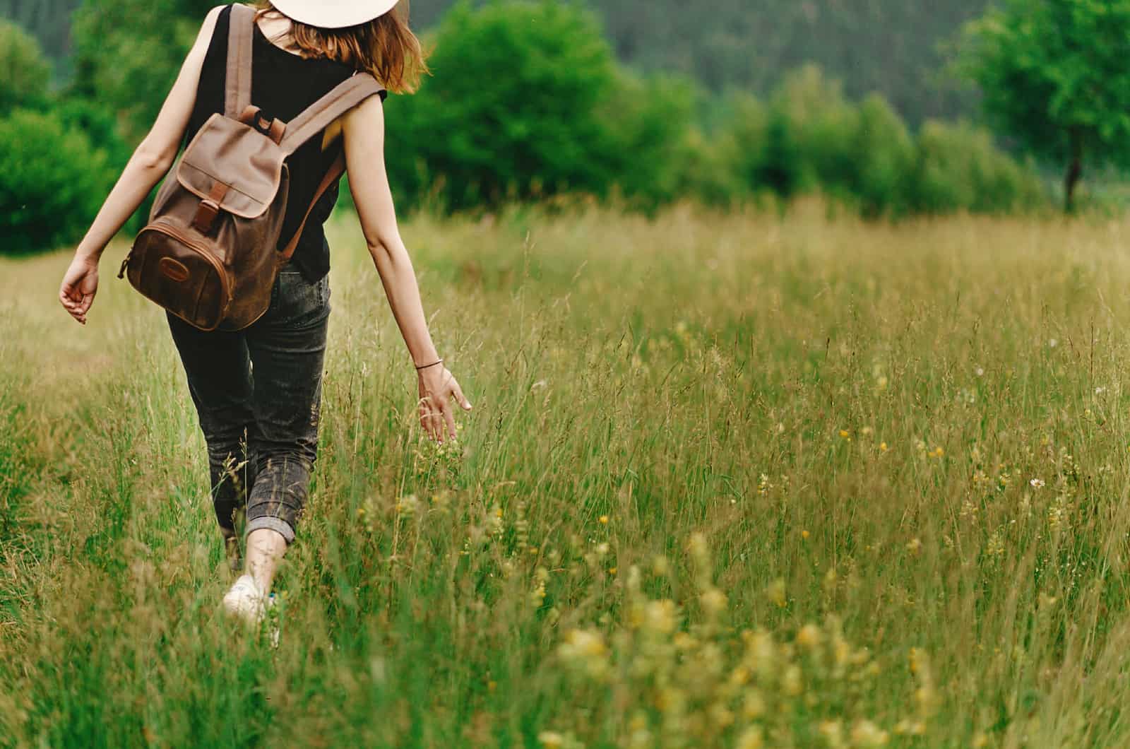 jeune femme marchant dans un champ d'herbe