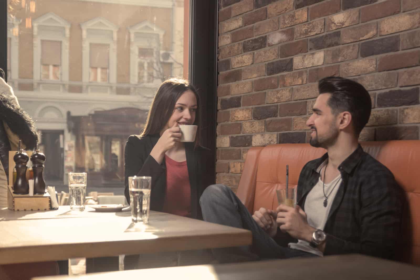 l'homme parle à la femme pendant qu'elle boit du café