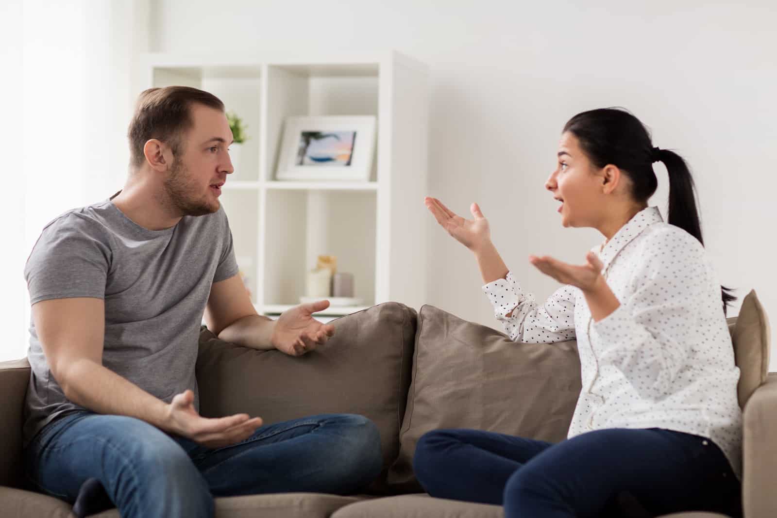 un homme et une femme s'assoient sur le canapé dans la maison et se disputent