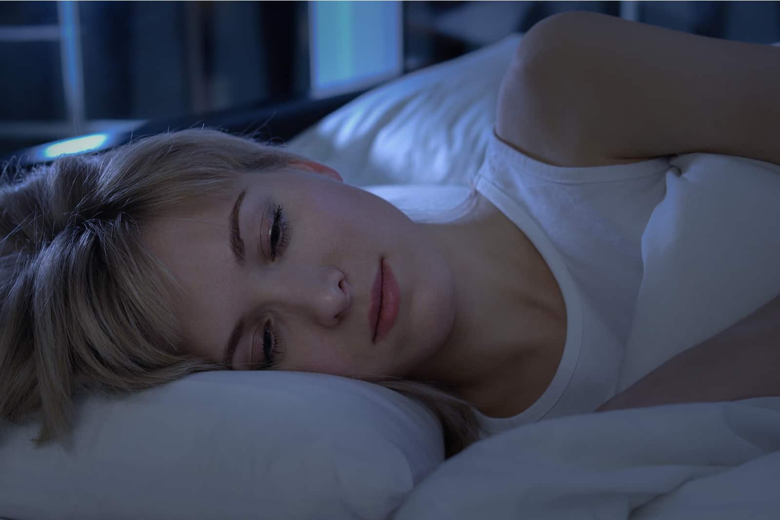 une femme aux cheveux blonds dort dans son lit