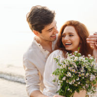 couple heureux sur la plage avec des fleurs