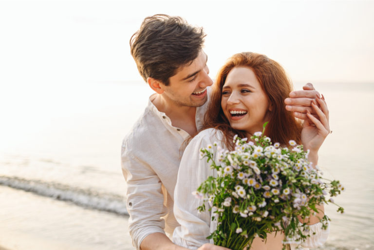 couple heureux sur la plage avec des fleurs