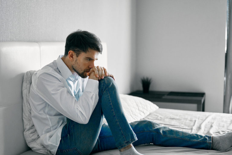 homme triste assis sur le lit