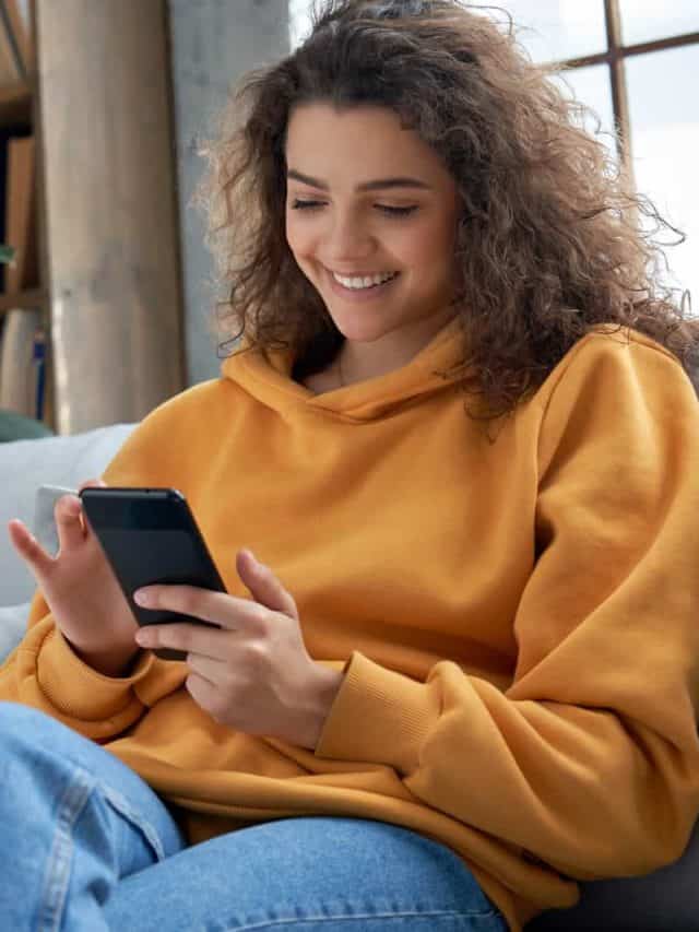 jeune femme envoyant des textos assise sur un canapé