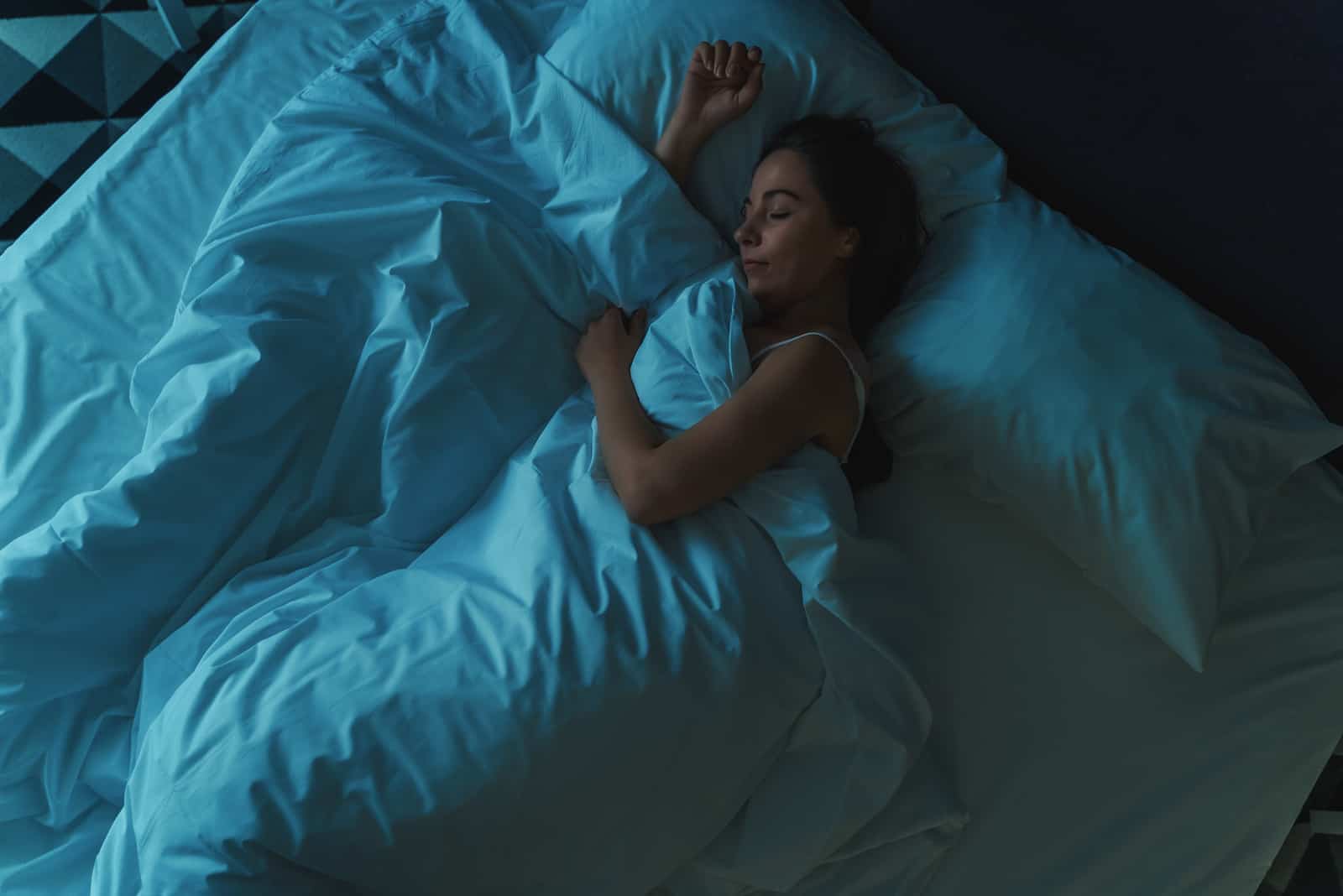 femme dormant sur le lit avec des draps bleus