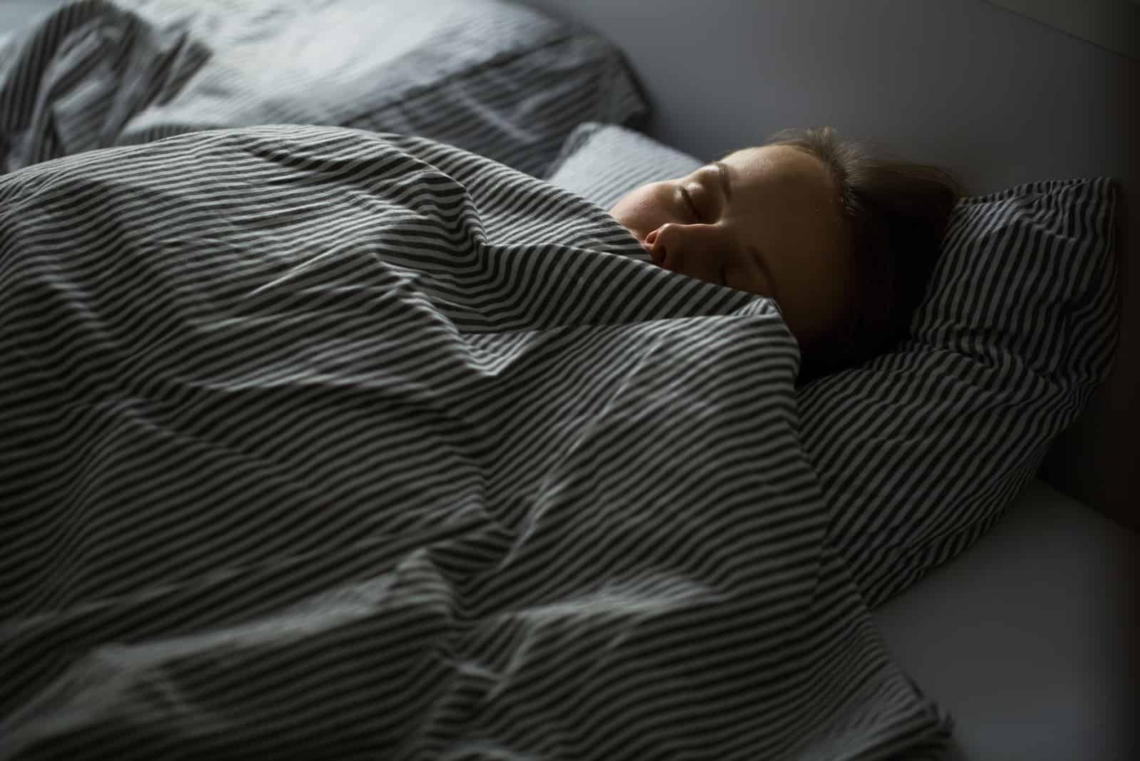 femme dormant sur le lit avec des draps rayés