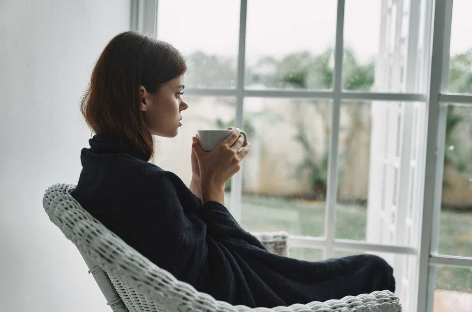 femme triste assise sur une chaise en train de boire du thé