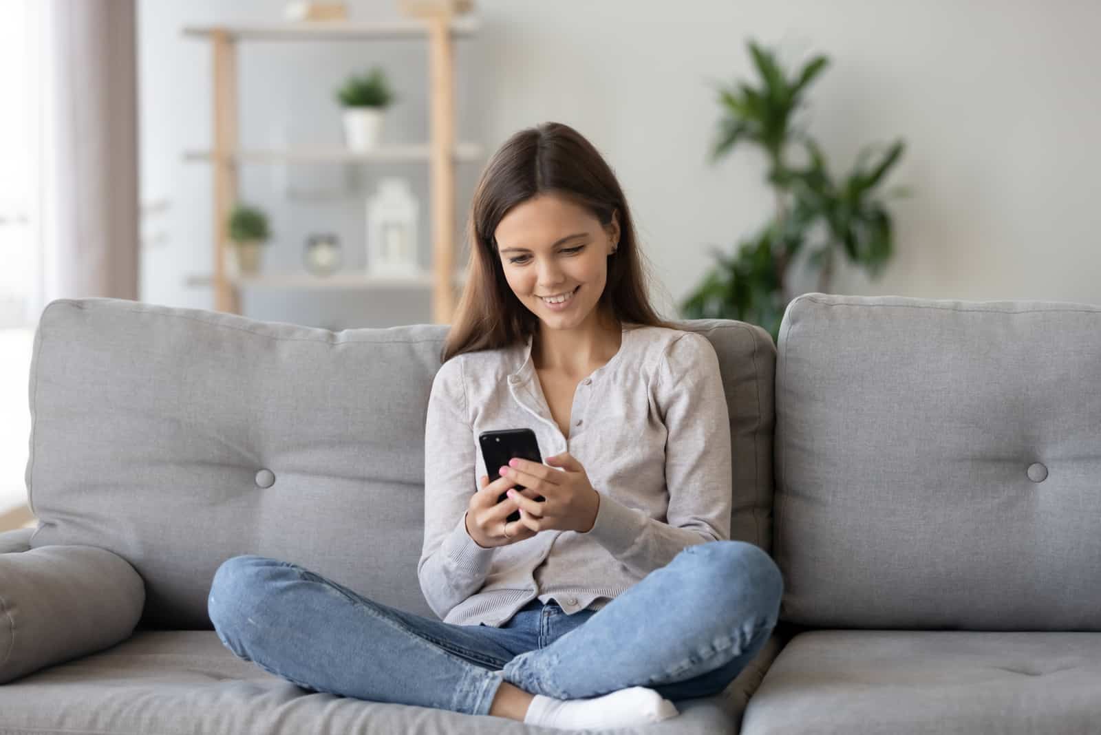 jolie fille assise sur un canapé envoyant des SMS