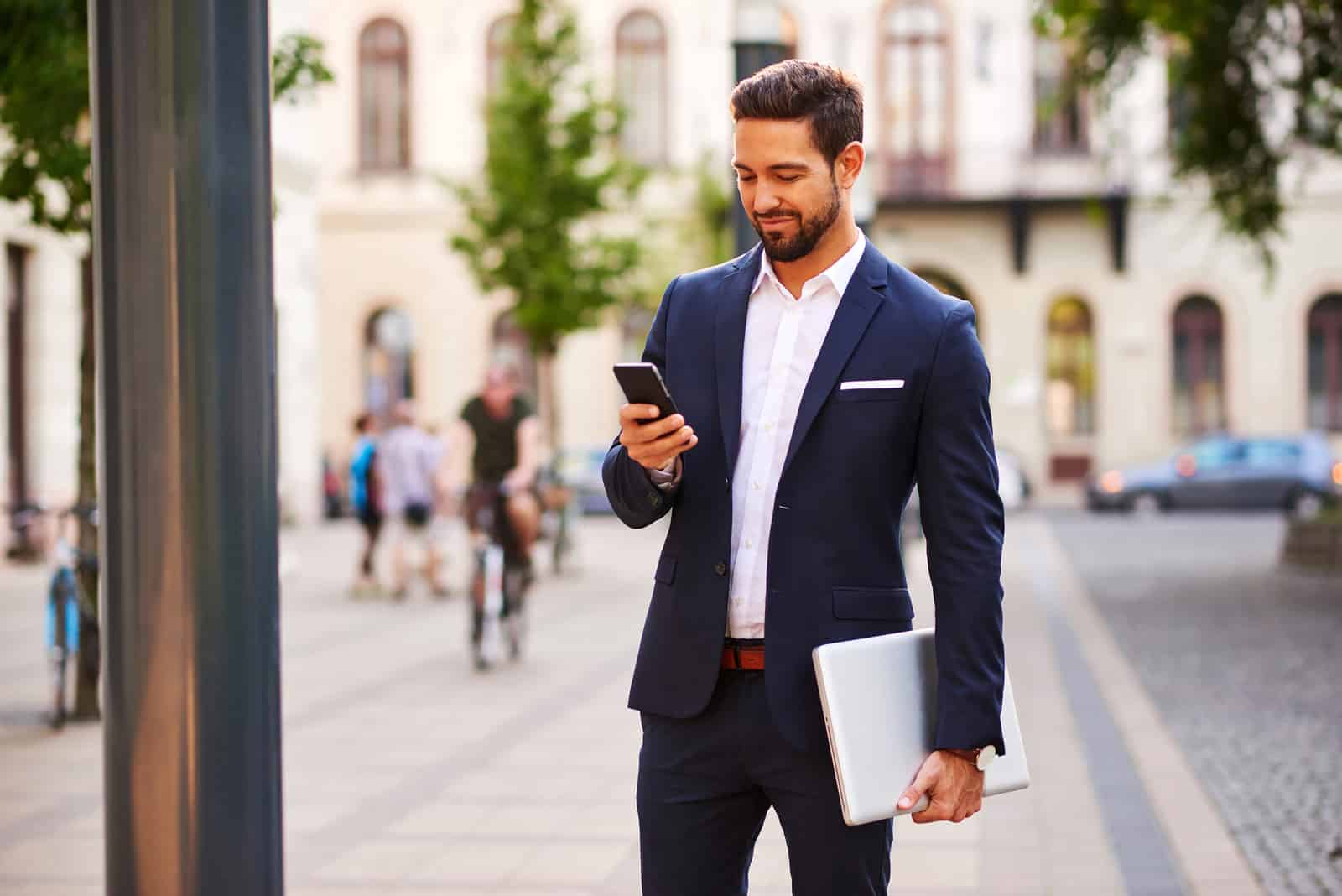 un homme en costume debout dans la rue et une clé sur son téléphone portable