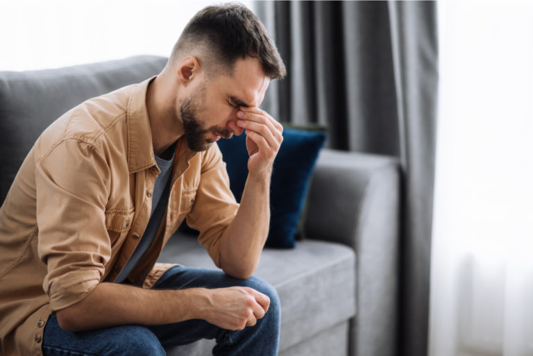 homme en détresse assis sur un canapé