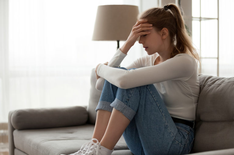 femme triste assise sur un canapé